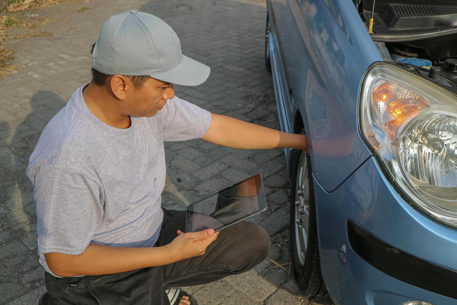 Expertise mechanic man in uniform using force trying to unscrew the wheel bolts nuts and help a woman for changing car wheel on the highway, car service, repair, maintenance concept. photo