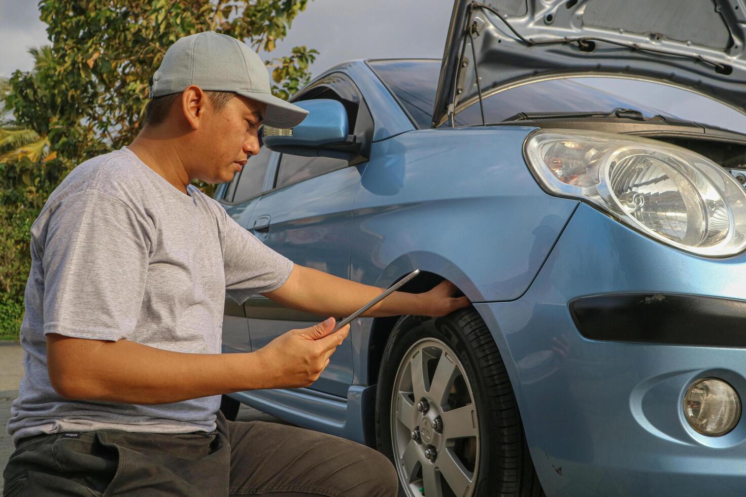 Asian men maintenance checking car service via insurance system at garage with using tablet photo