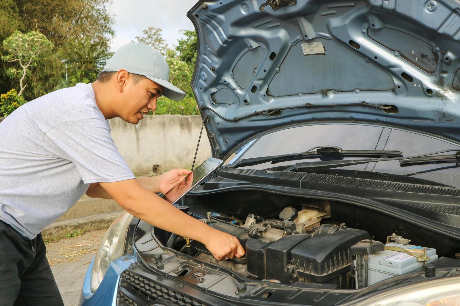 Professional car mechanic maintenance vehicle. The mechanic opens the front of the car. Checking the broken engine. Check the damage as listed. Repair car outside service. photo