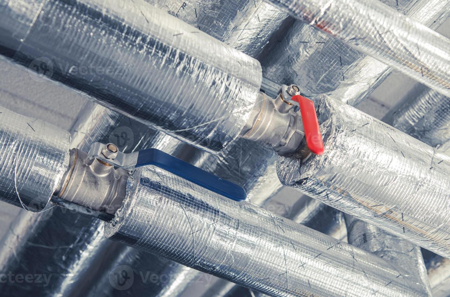 Valve Controls on Insulated Metal Pipes in an Industrial Setting Under Bright Lighting photo