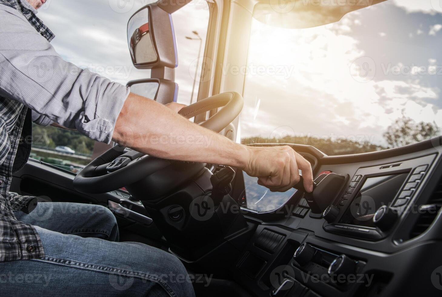 Driver Adjusting Controls While Operating a Large Truck During Sunset on the Highway photo