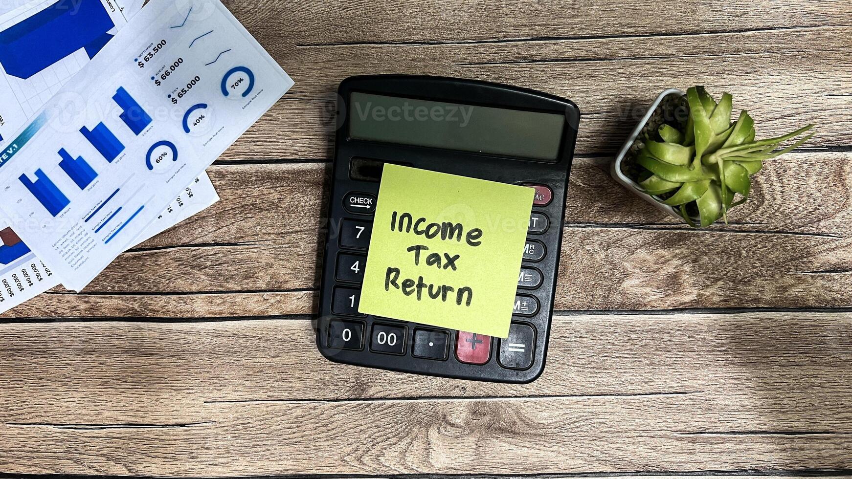 Concept of Income Tax Return write on sticky notes isolated on Wooden Table. photo