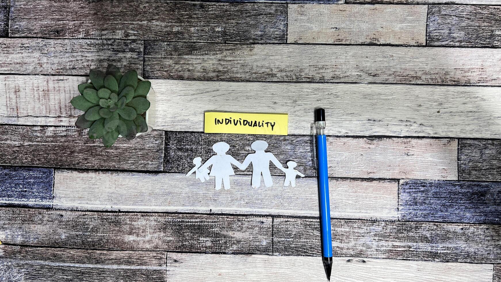 Concept of Individuality write on sticky notes isolated on Wooden Table. photo