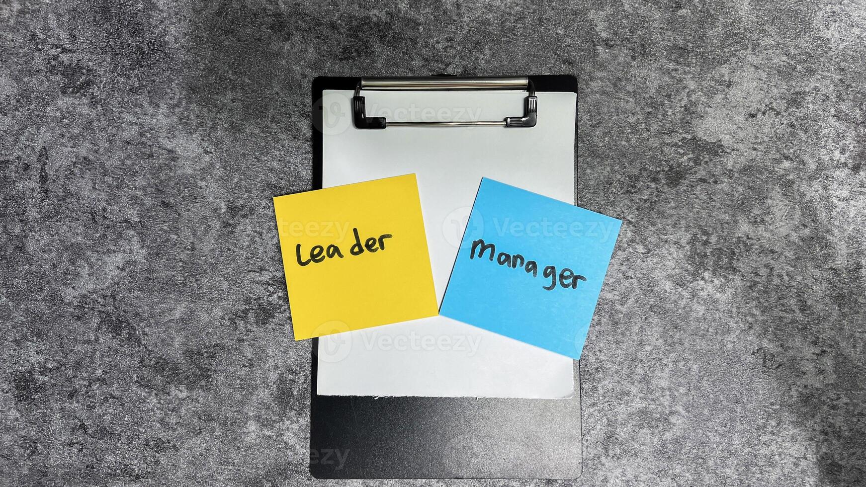Concept of Leader vs Manager write on sticky notes isolated on Wooden Table. photo