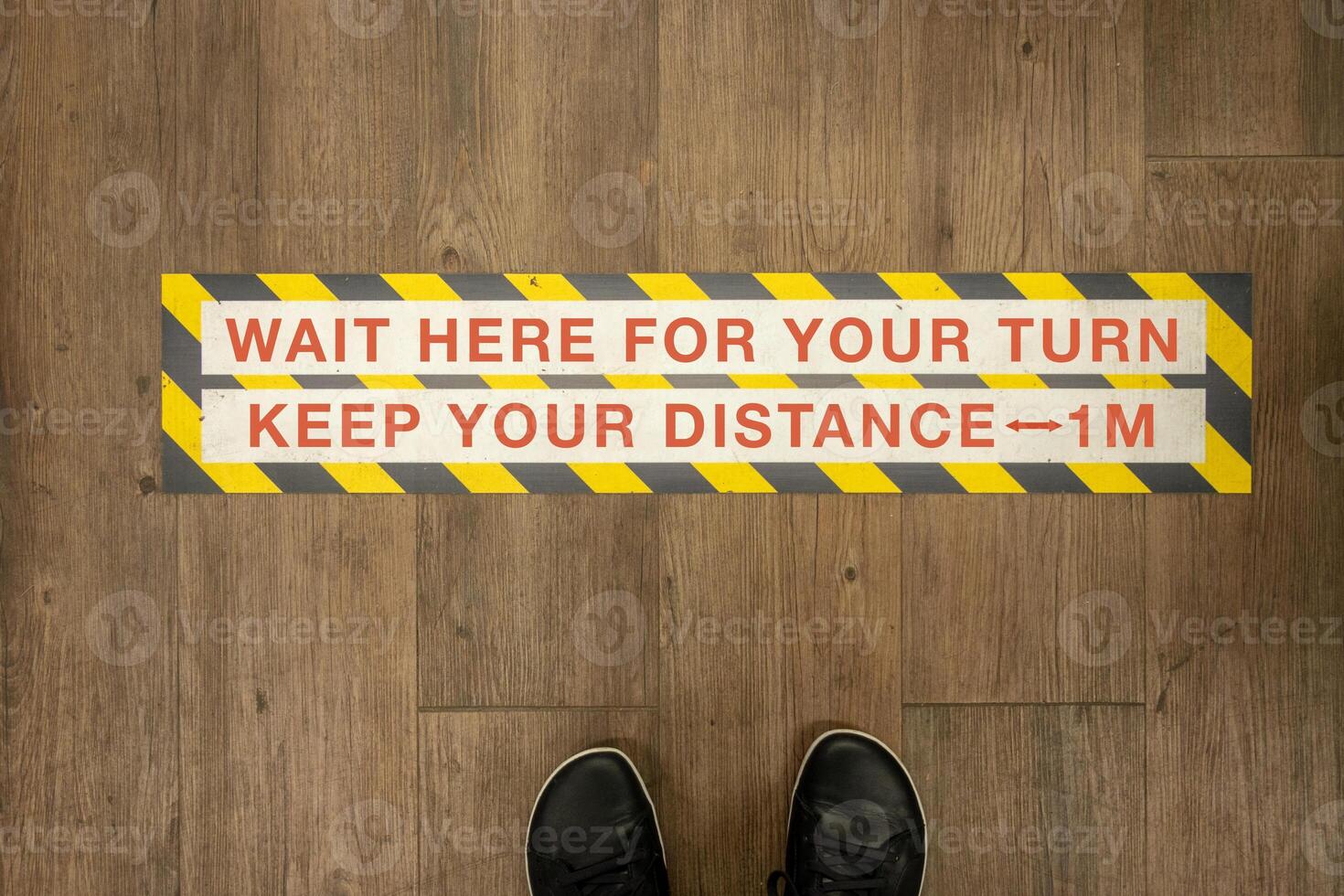 Wait your turn, keep your distance sign on a store floor. photo