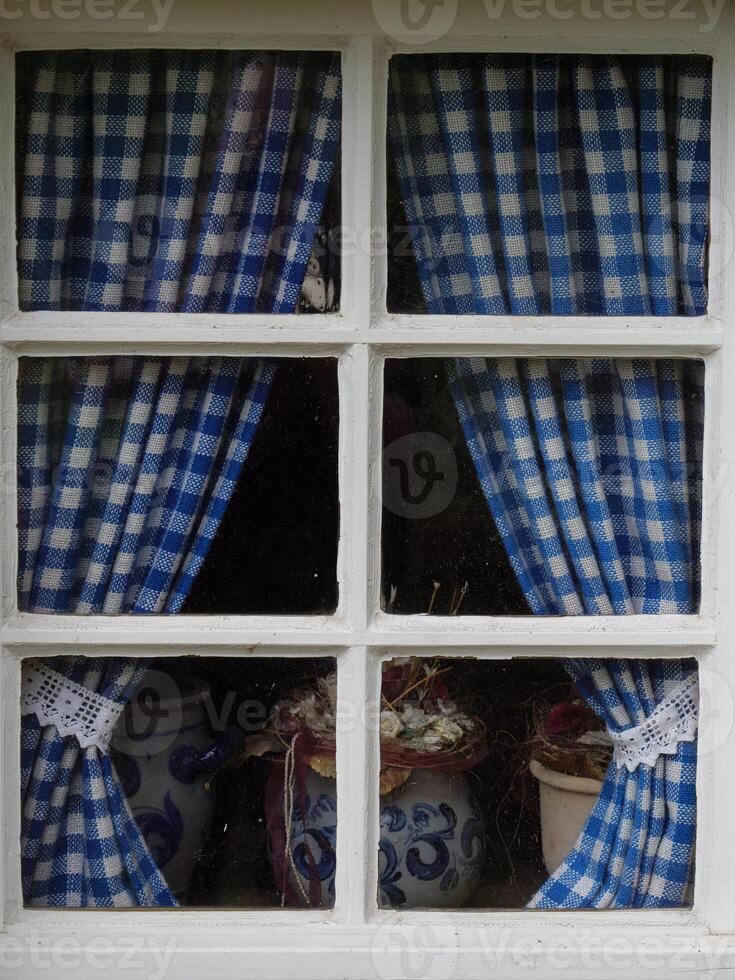 A window with blue and white checkered curtains photo