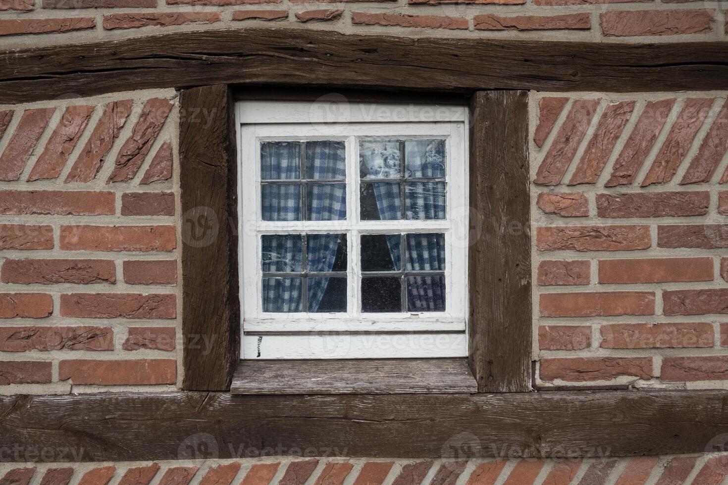 A window in a brick wall with a blue curtain photo
