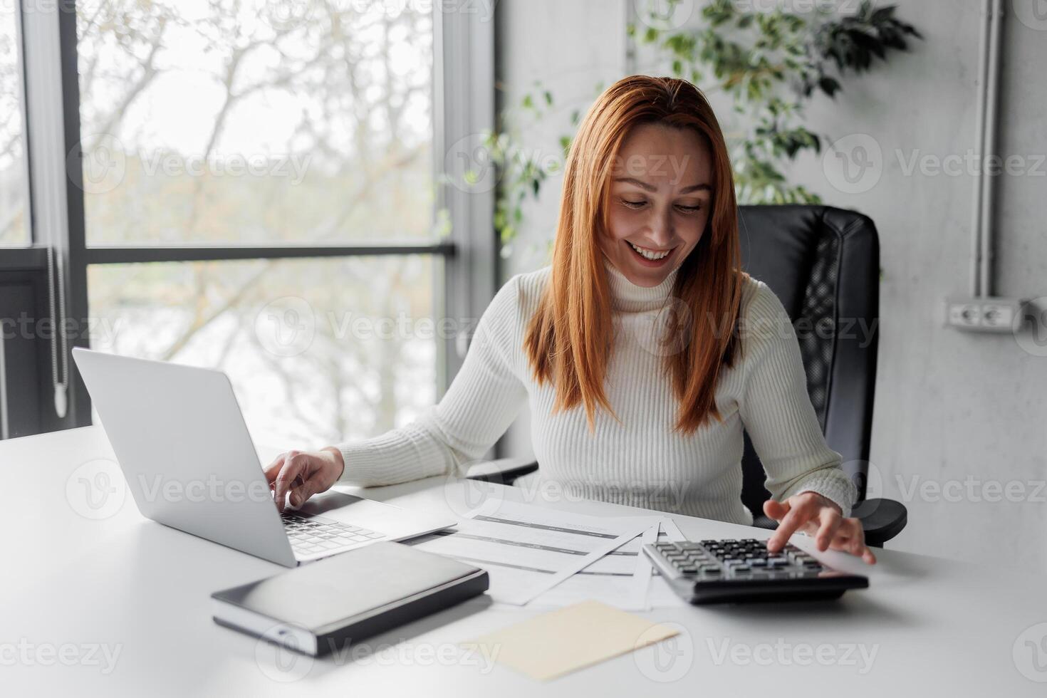 Financial advisor calculating and working in an office. Cheerful mid aged accountant at her desk. Happy woman calculating. photo
