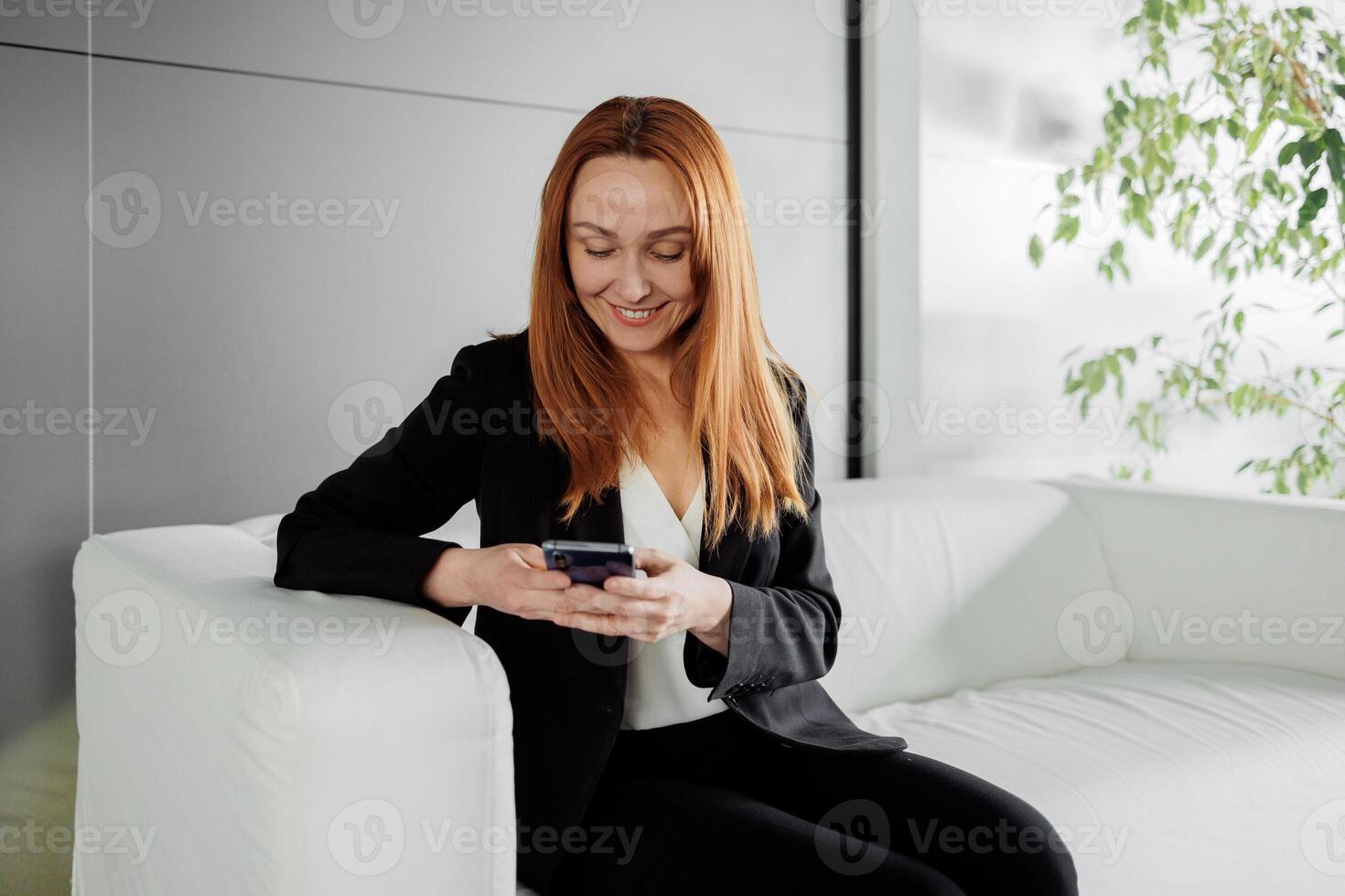 Smiling middle-aged female employee wearing glasses makes a call at work while sitting at her desk and talking to a client or customer on the webcam. photo