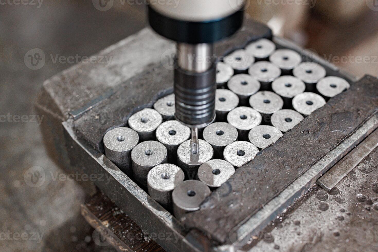 Precision in Motion A drill press expertly machining gleaming metal cylinders, creating perfectly crafted components with every calculated turn. photo