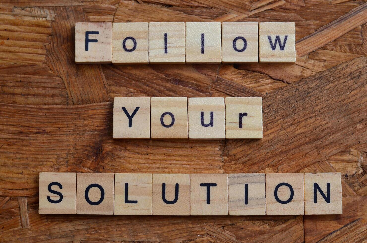 follow your solution text on wooden square background photo