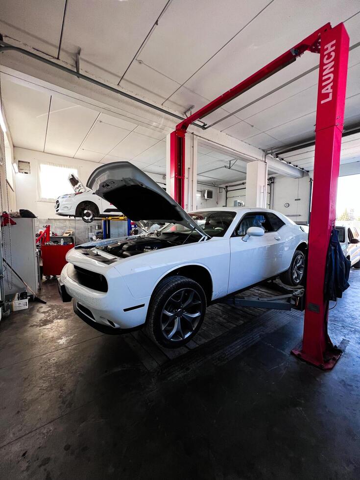 Kyiv, Ukraine - November 22, 2024 Modern auto repair shop with Dodge Challenger car on hydraulic lift photo