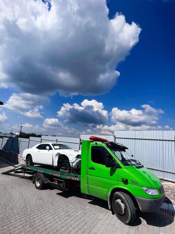 Kyiv, Ukraine - November 22, 2024 Bright green tow truck transporting Dodge Challenger vehicle under a cloudy sky photo