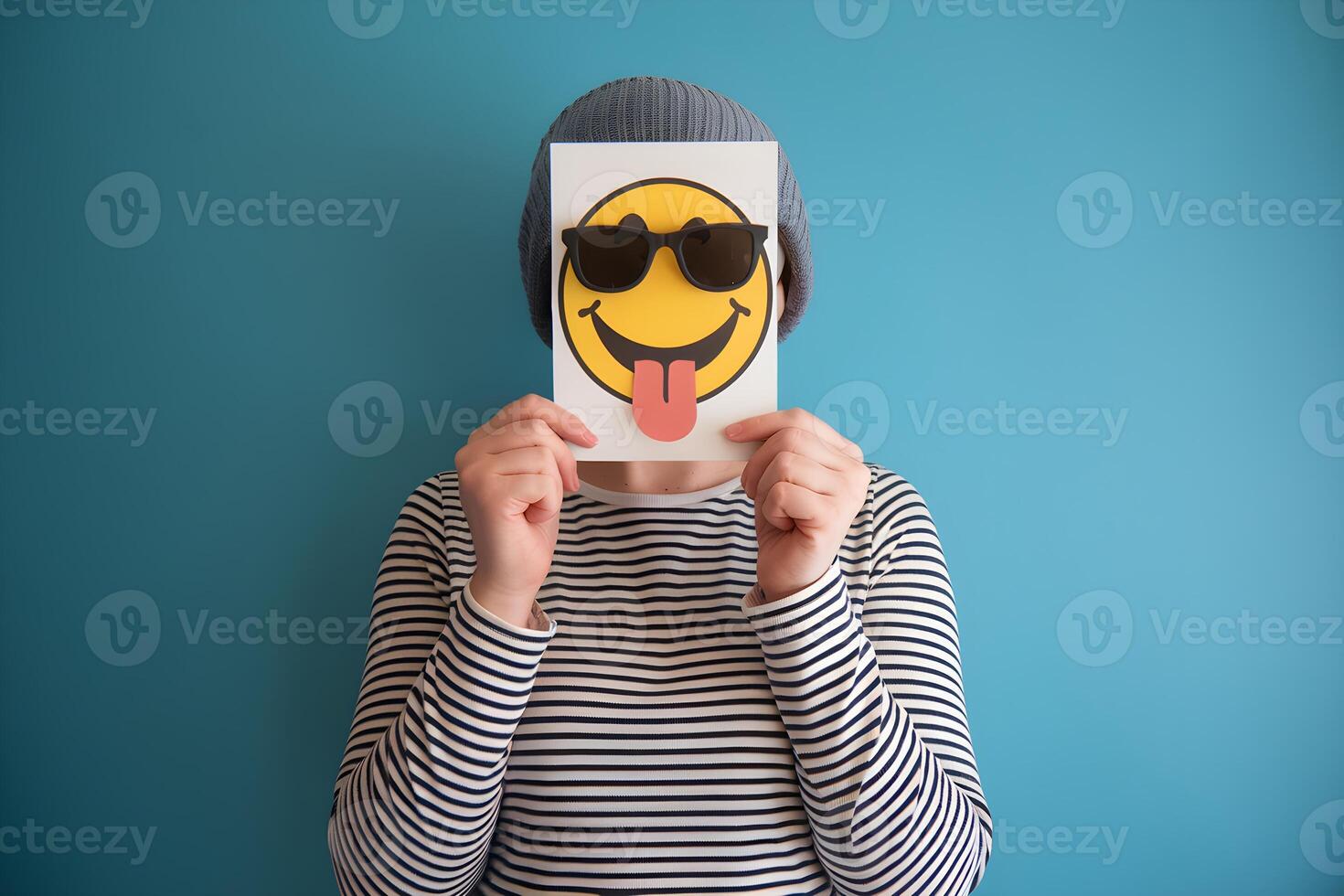 Card with smiley face hides persons face, playful tone against blue background photo