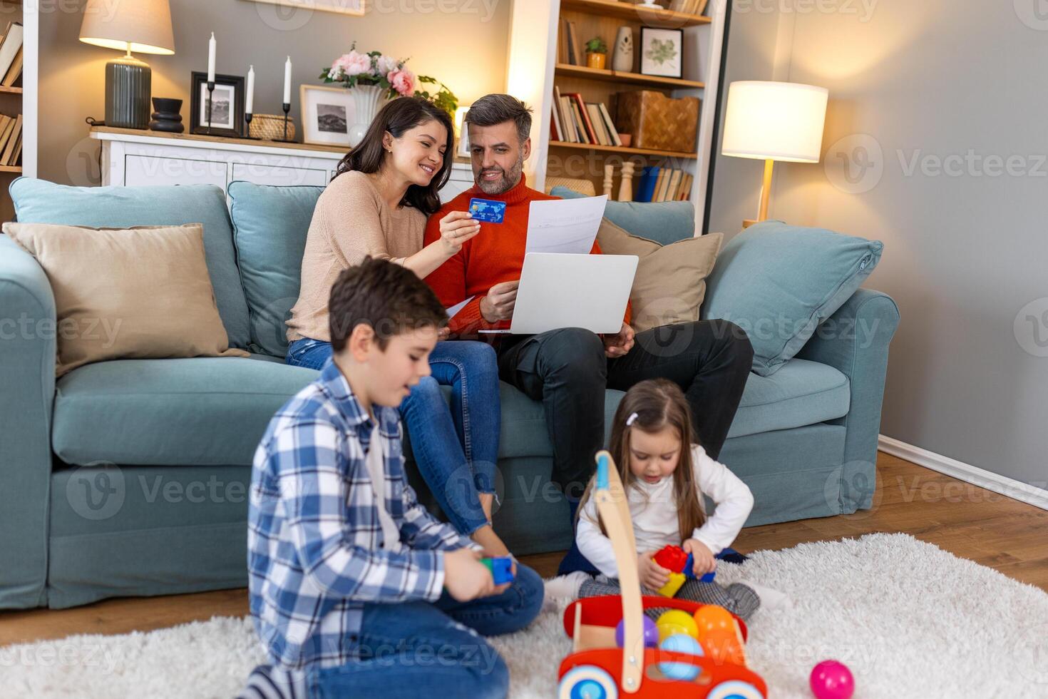A family sitting on a couch with a laptop and toys photo