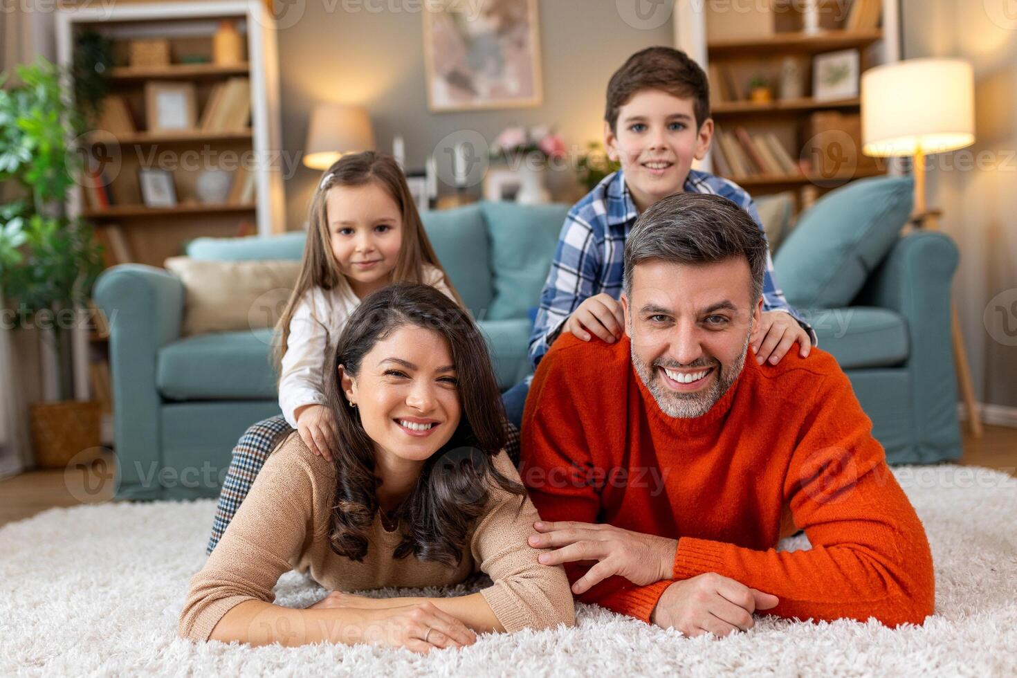 A family is sitting on a rug in a living room photo