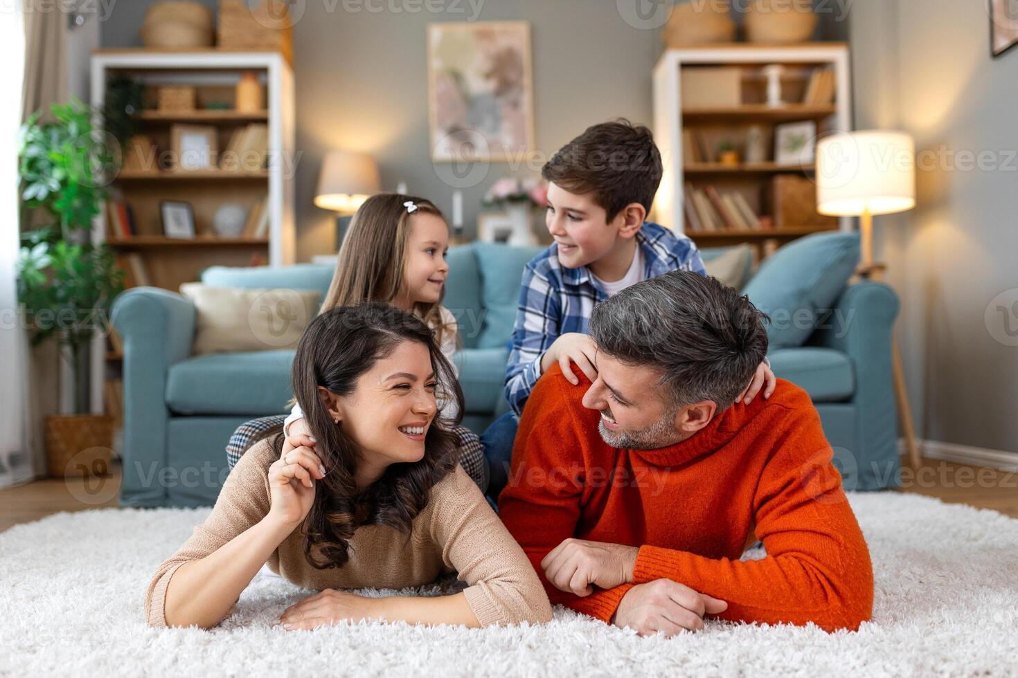 A family is lying on a rug in a living room photo
