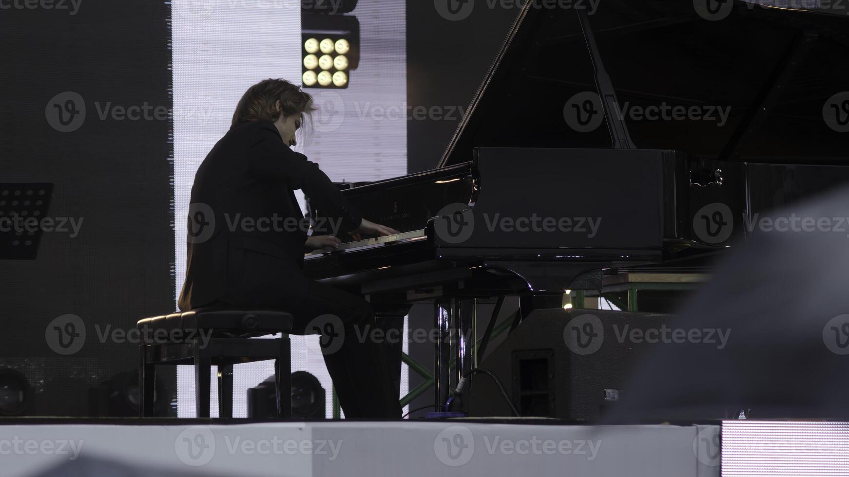 A talented pianist mesmerizing the audience while performing on stage surrounded by umbrellas. Clip photo
