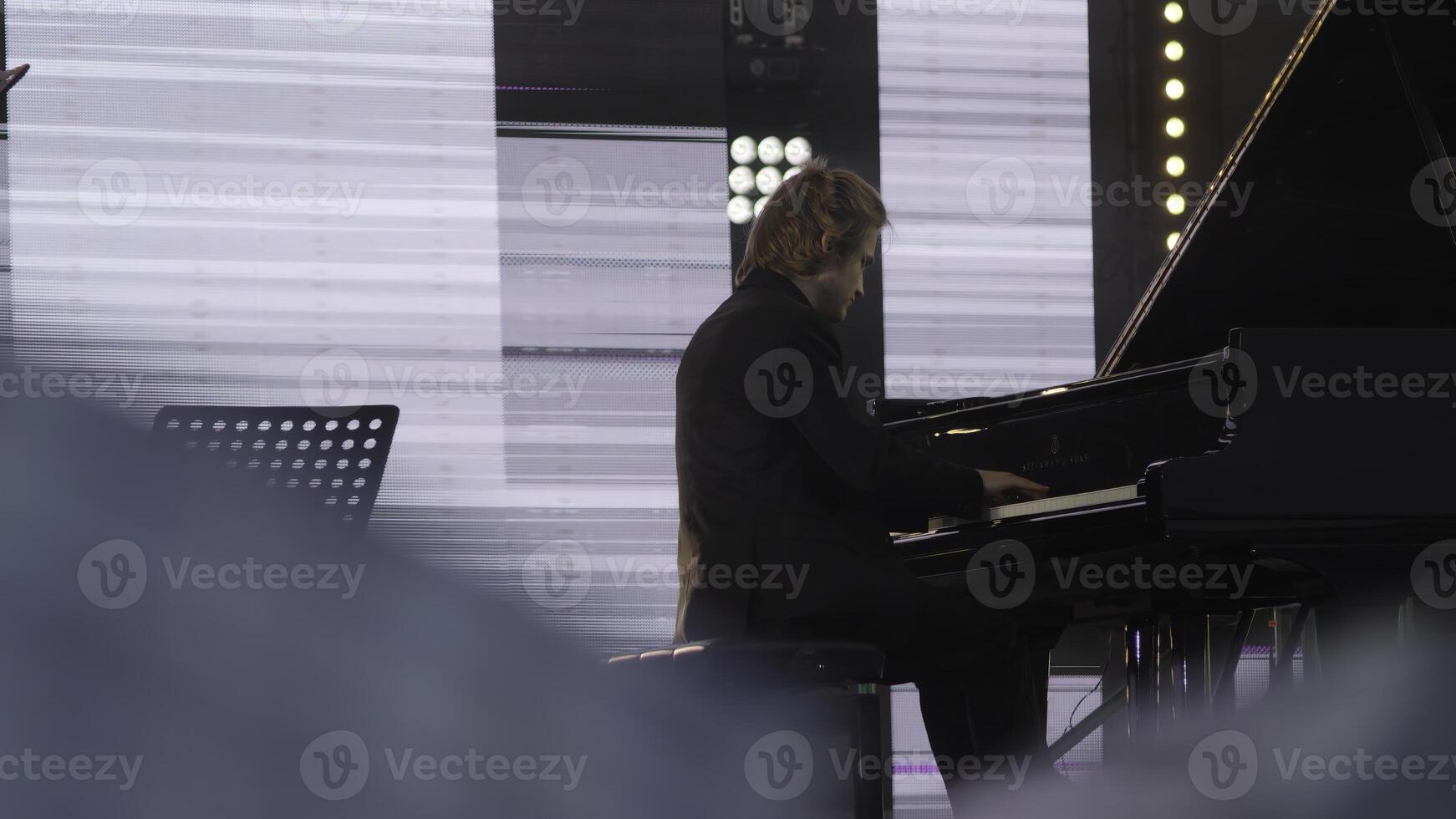 A talented pianist is performing live on stage at an exciting music festival event. Clip photo