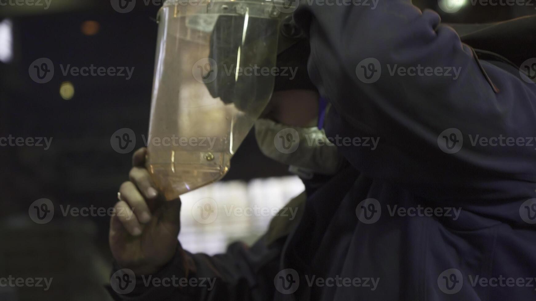 A skilled worker carefully analyzing materials under challenging low light conditions in a factory. Stock Clip photo