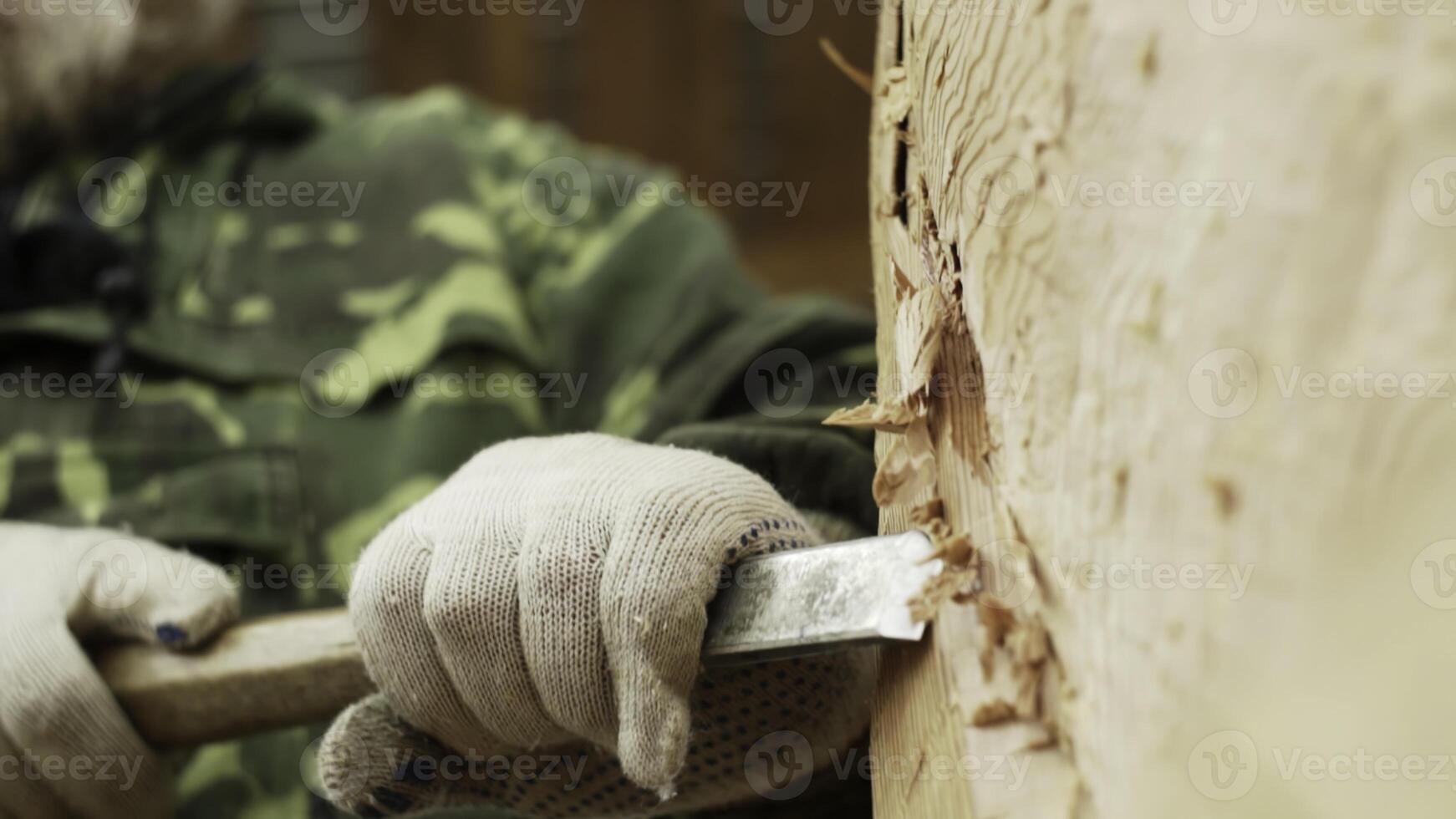 Skillfully Hand Carving Beautiful Wood with a Chisel While Dressed in Camouflage Gear. Stock Clip photo