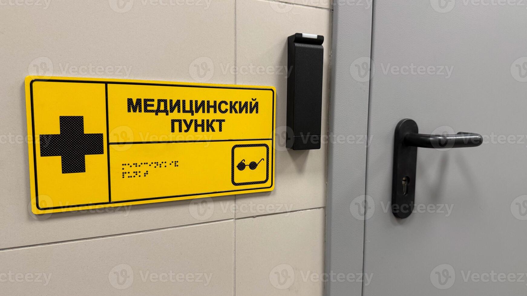 Entrance to medical center at station to assist passengers, sign with medical sign and braille text to indicate place of first aid in public place. Inscription in Russian - medical station photo
