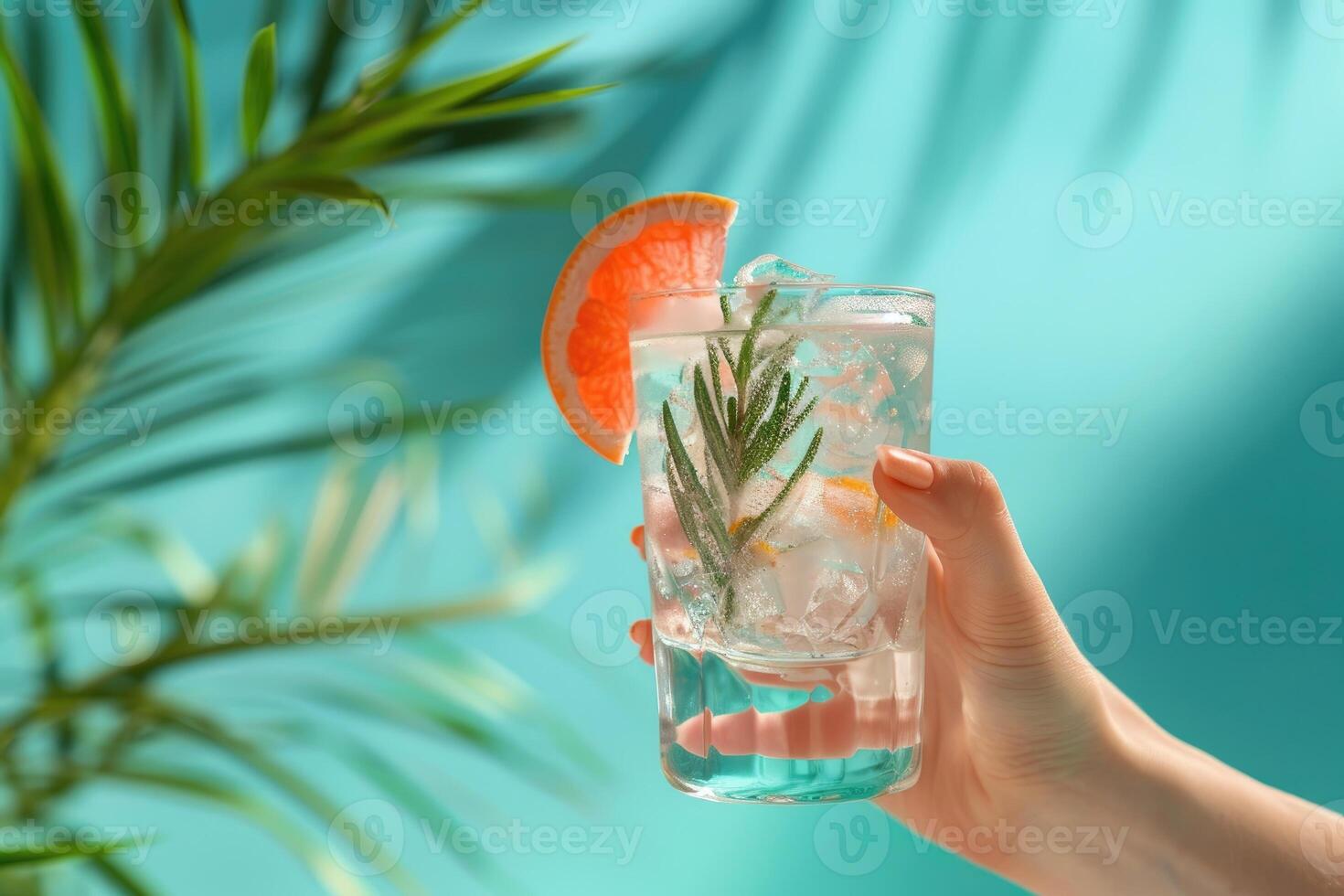 Summer concept - hand holding gin and tonic coctail, solid color background photo