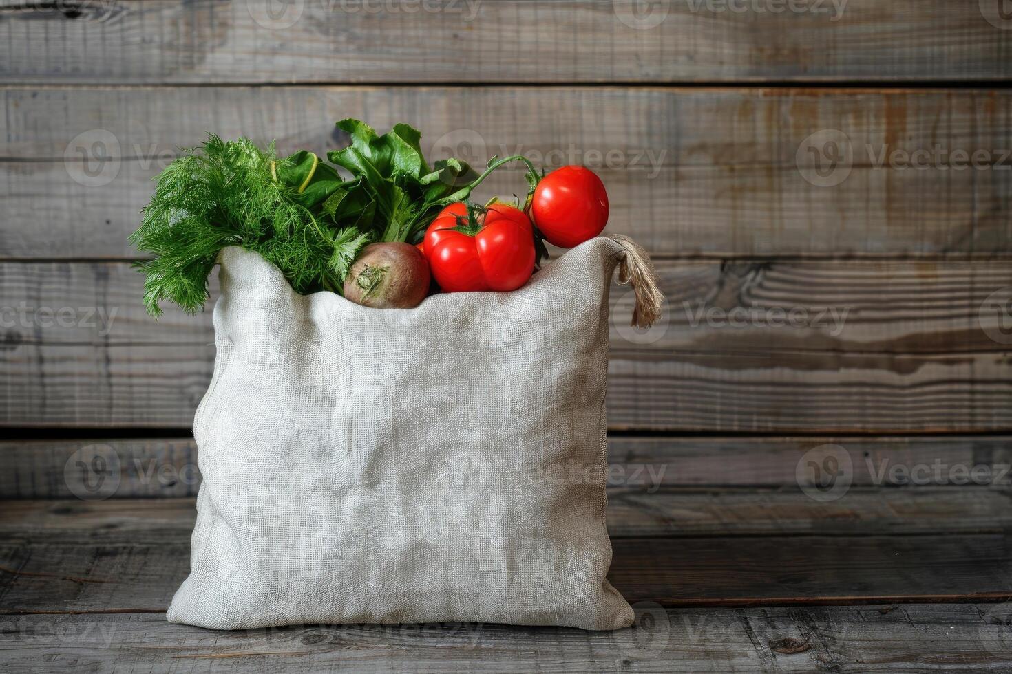 White linen bag with vegetables is placed on a rustic wooden background photo