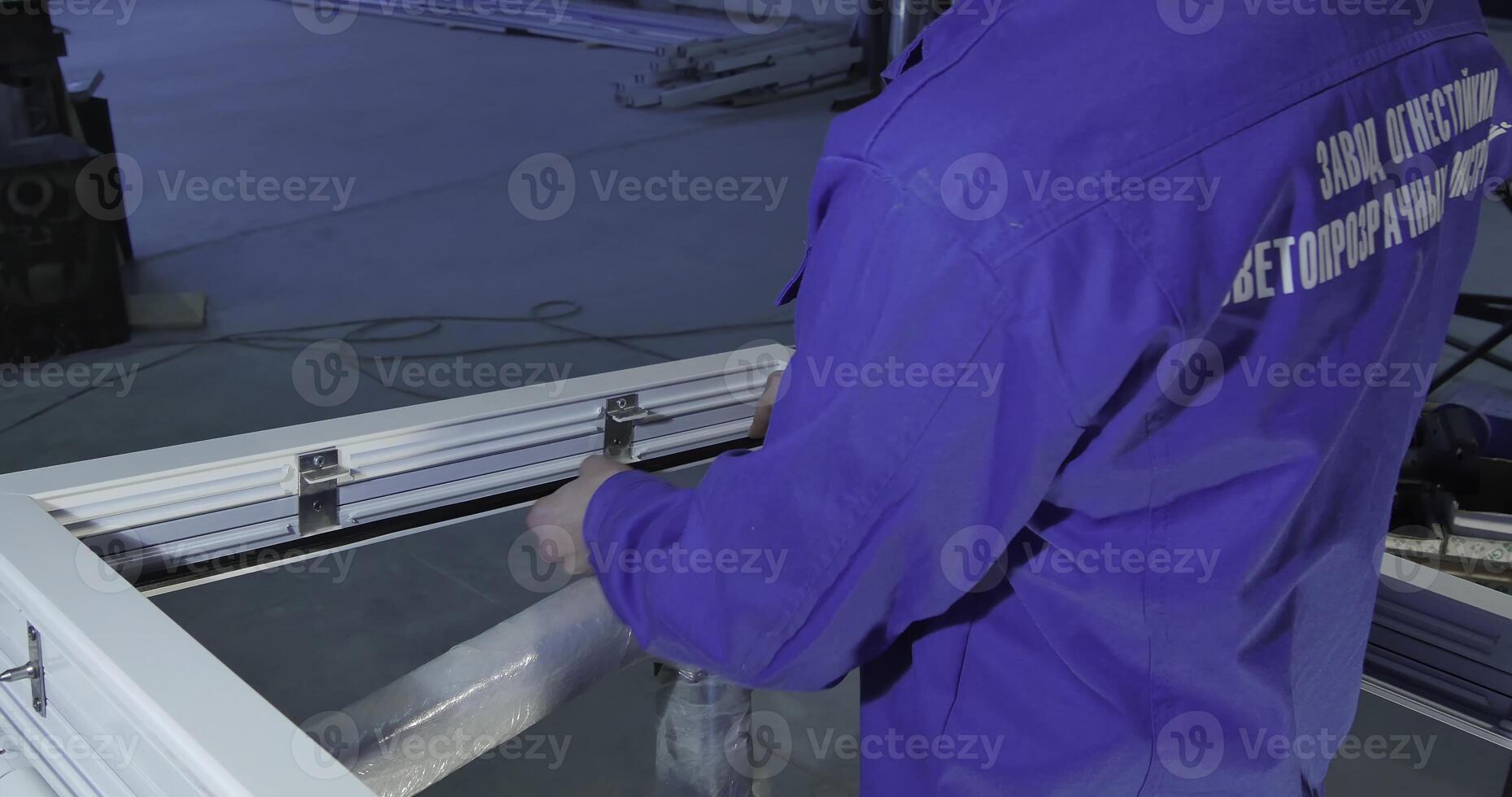 A skilled man in a blue jacket works on metal and window structures photo