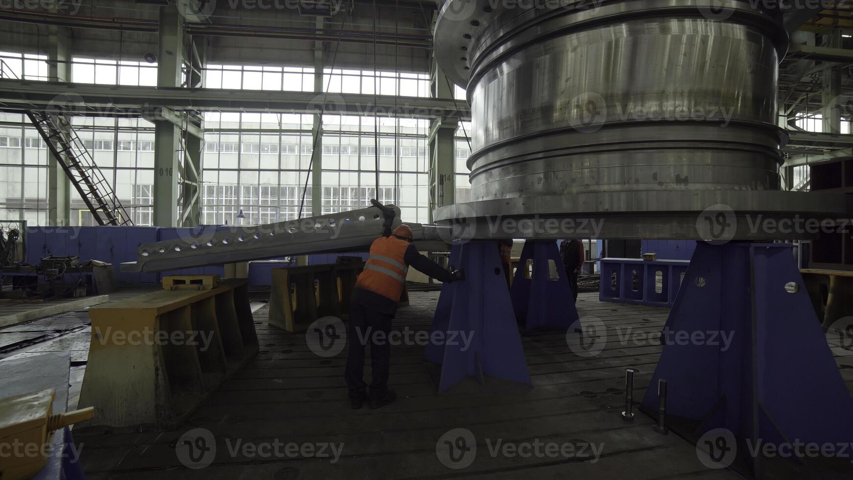 An Industrial Worker Actively Handling a Large Machinery Component Inside a Factory Environment. Stock Clip photo