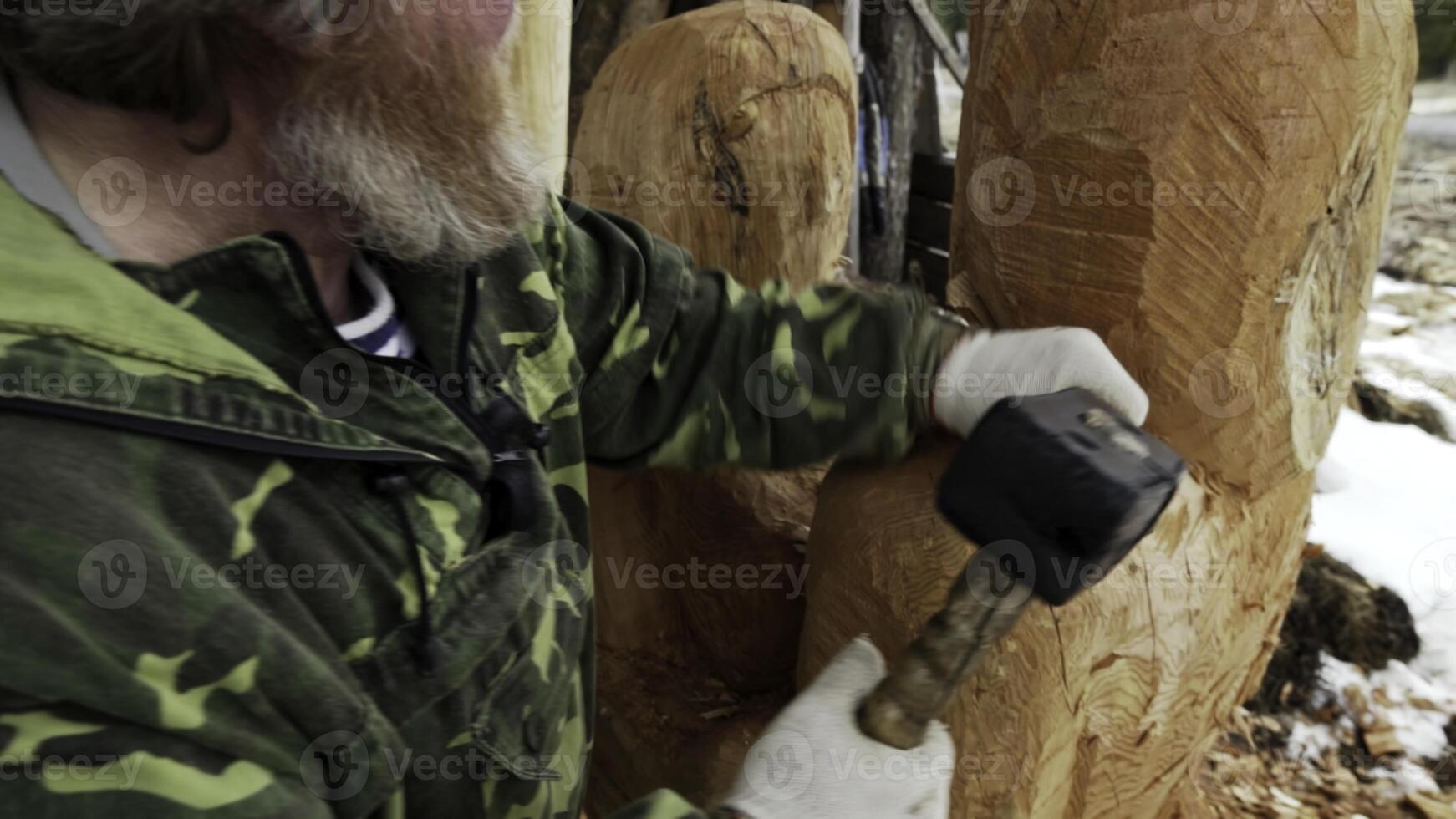 A skilled craftsman meticulously carves an intricate wood sculpture using a hammer and chisel. Stock Clip photo