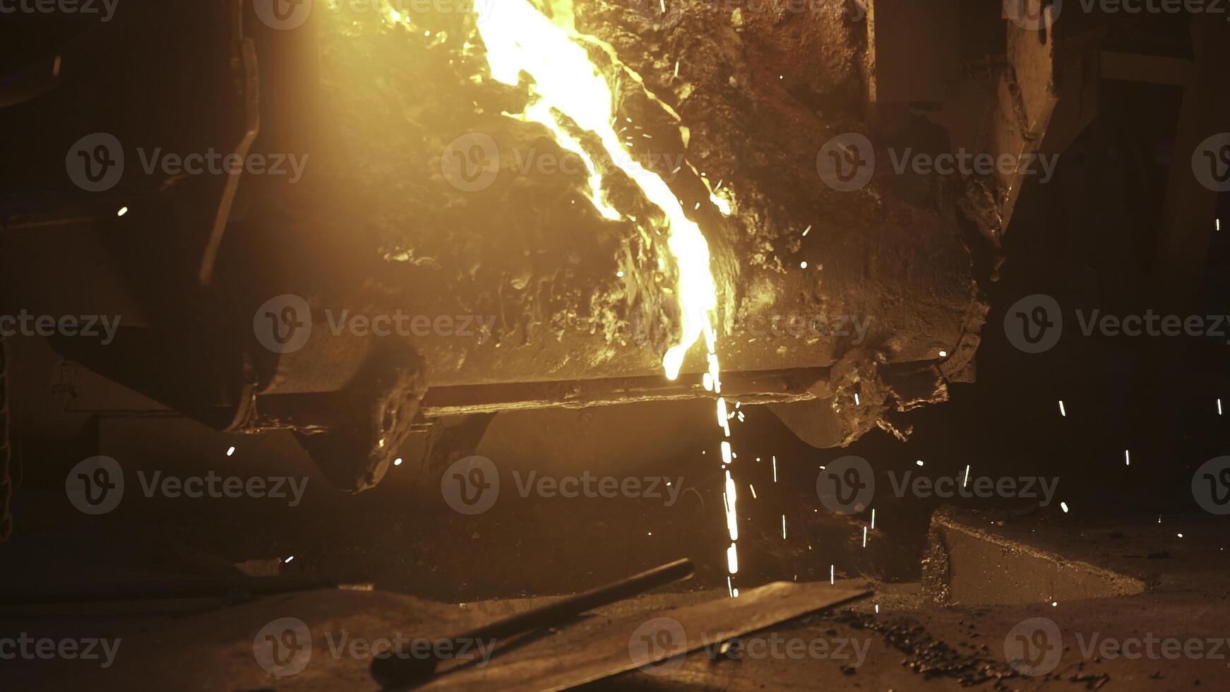 Molten metal is being poured out, producing bright sparks within a vibrant foundry environment. Stock Clip photo