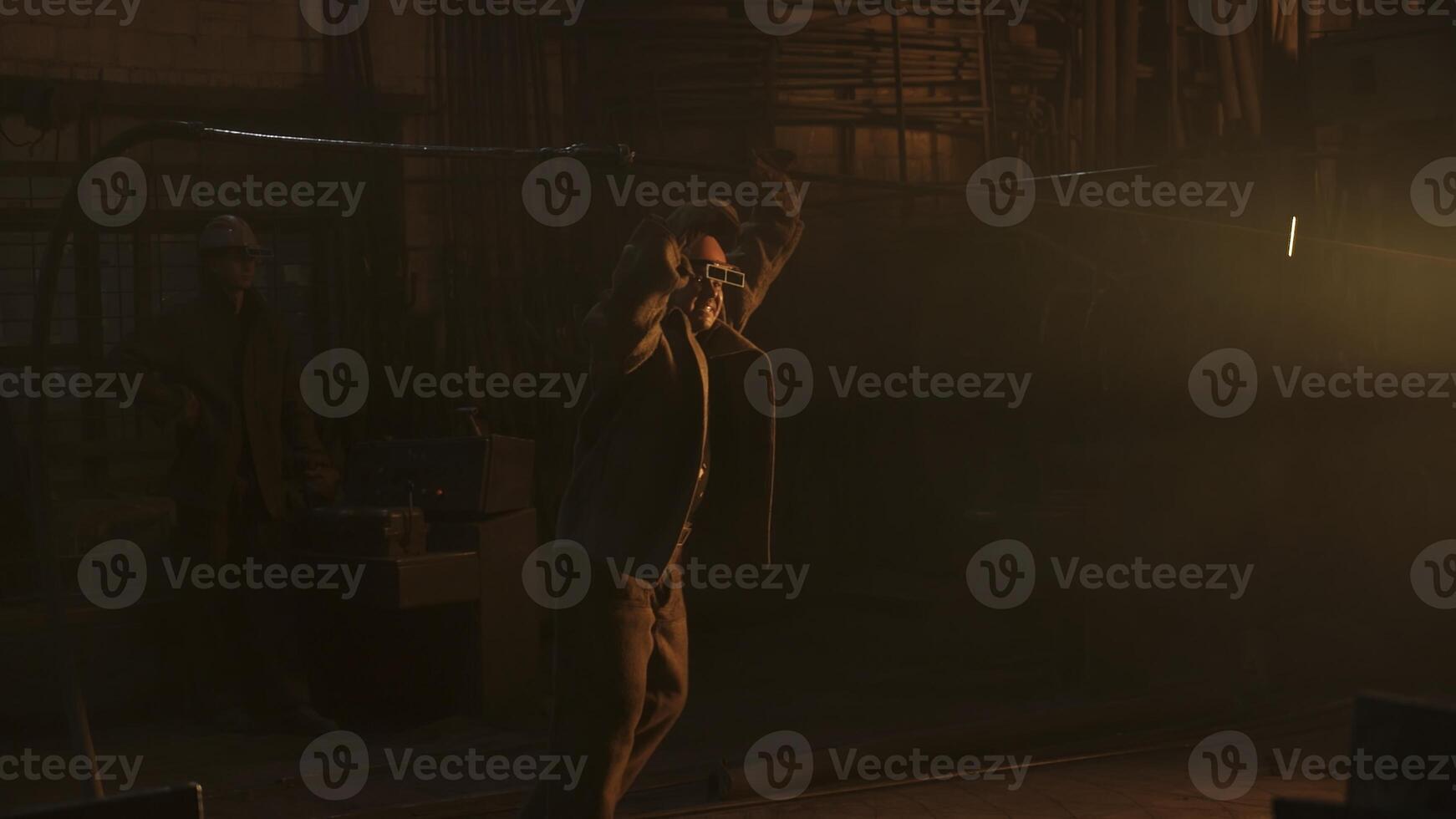 A worker laboring in a dim industrial setting, demonstrating craftsmanship and dedication. Stock Clip photo
