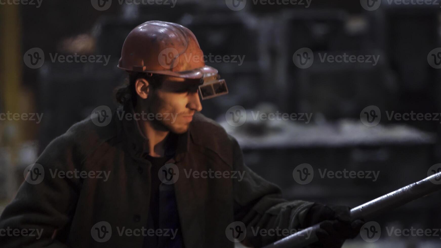 A worker wears a safety helmet and goggles for protection in an industrial setting. Stock Clip photo