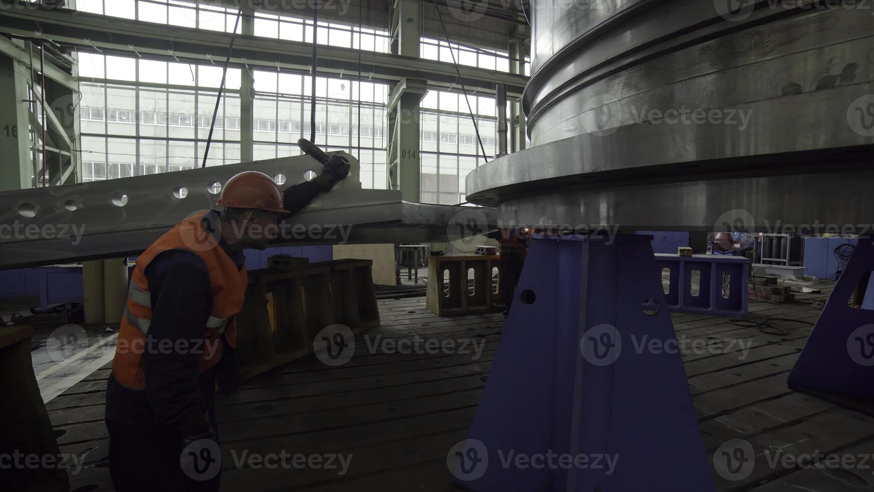 A worker is thoroughly inspecting a large piece of industrial machinery within a factory. Stock Clip photo