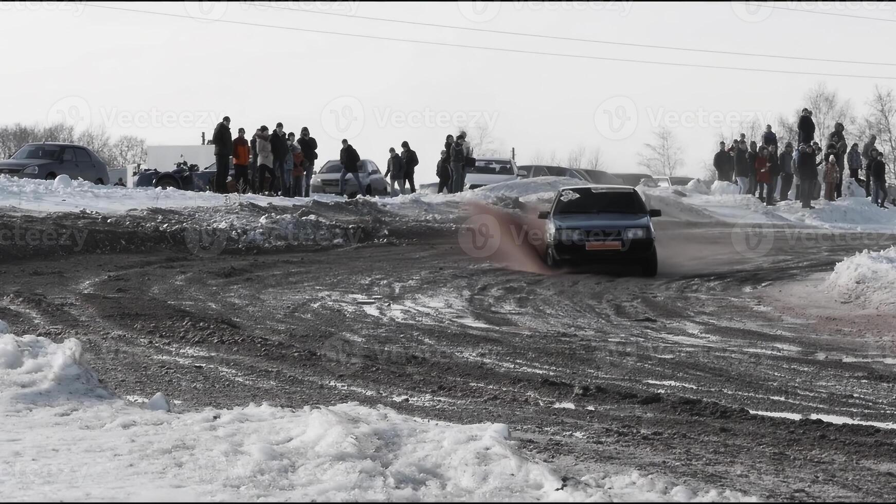 Skilled driver navigates a car through a snowy landscape, impressing a crowd photo