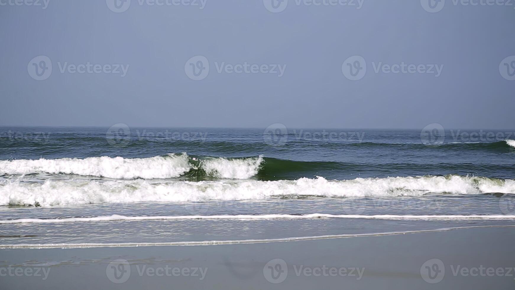 The soothing and tranquil ocean waves gently lap against the shore on a sunny day. Stock Clip photo