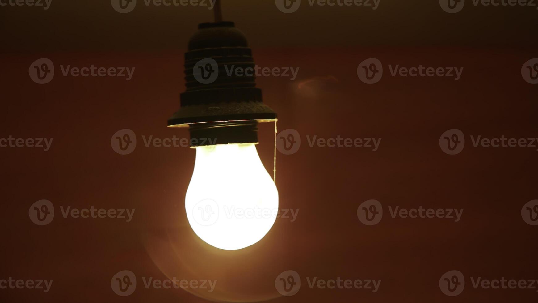 A Glowing Red Light Bulb Brightly Illuminating a Dark Setting for an Intimate Atmosphere. Stock Clip photo