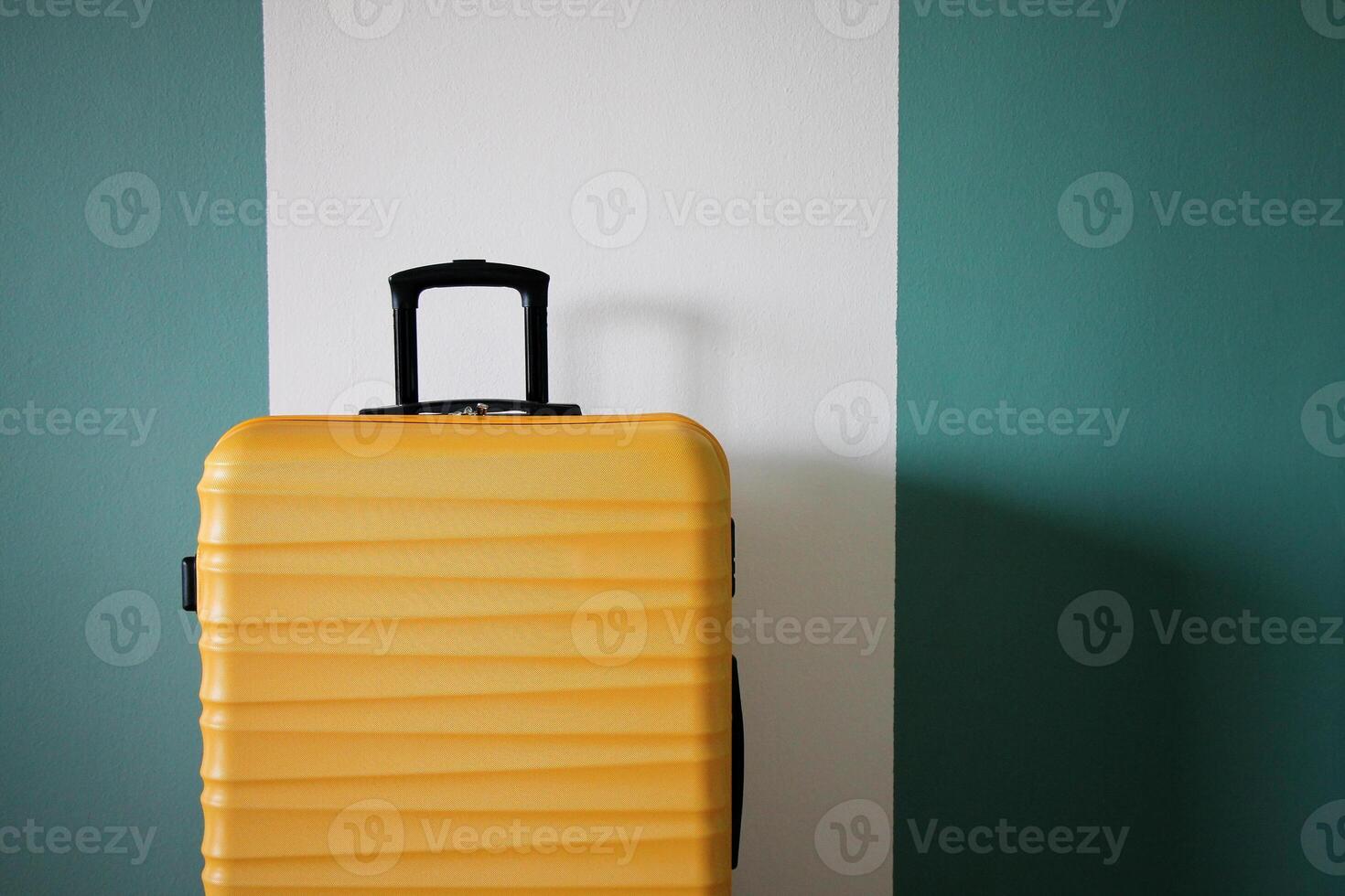 New yellow suitcase against the wall. Travel and vacation concept. photo
