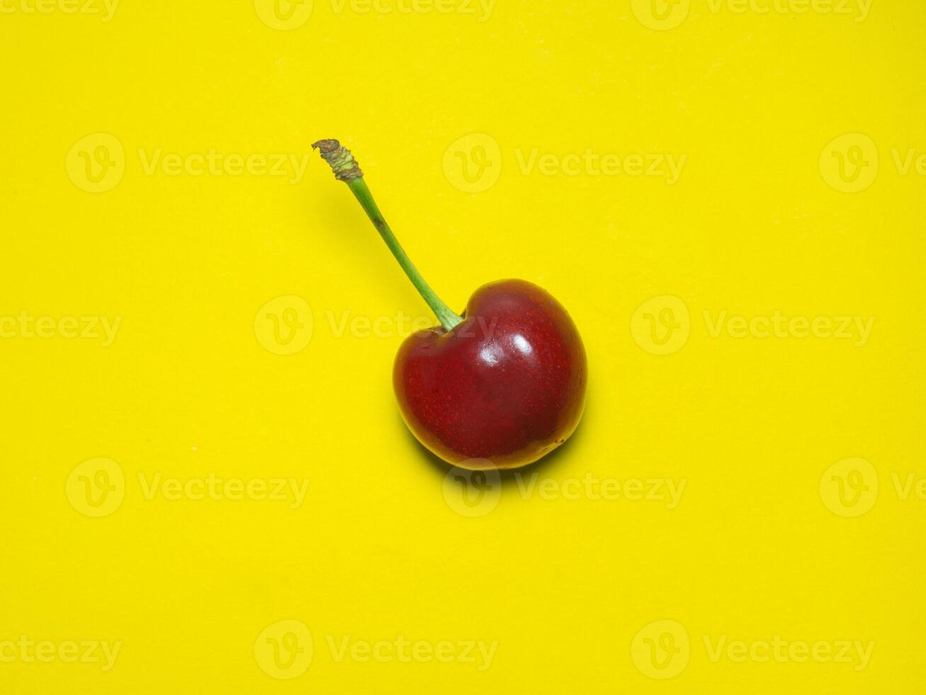 bright ripe sweet cherry on a yellow background. Berry with stem. Cherry isolate. Ingredient for jam and compote. photo