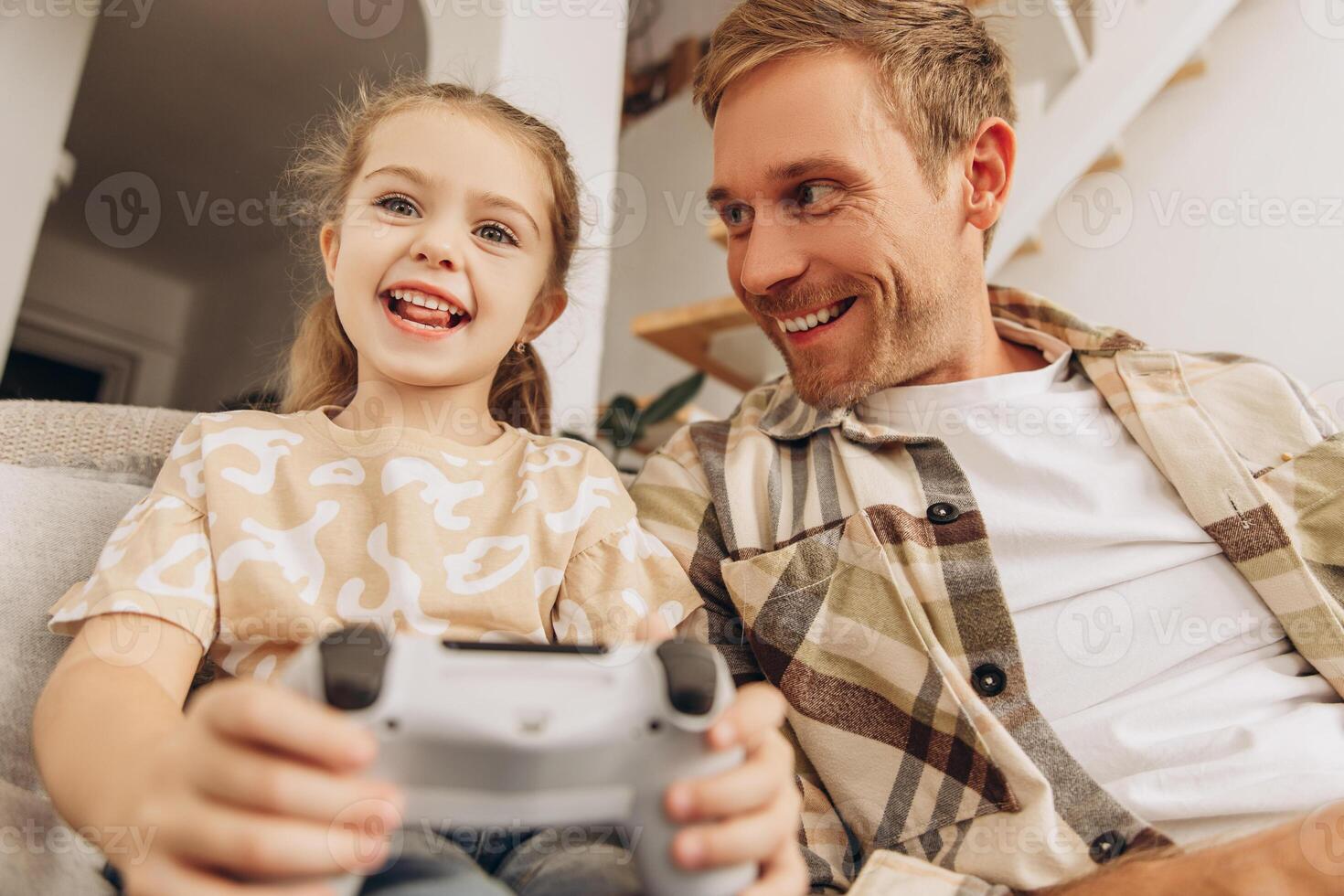 Portrait of positive man, little daughter and father playing together game, holding console photo
