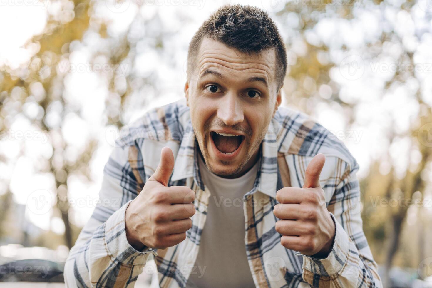 Portrait of overjoyed, handsome man wearing casual clothes showing thumb up, with open mouth photo