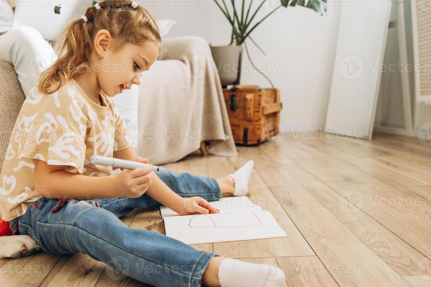 Beautiful, smiling, cute little girl drawing, sitting on floor in living room at home, copy space photo