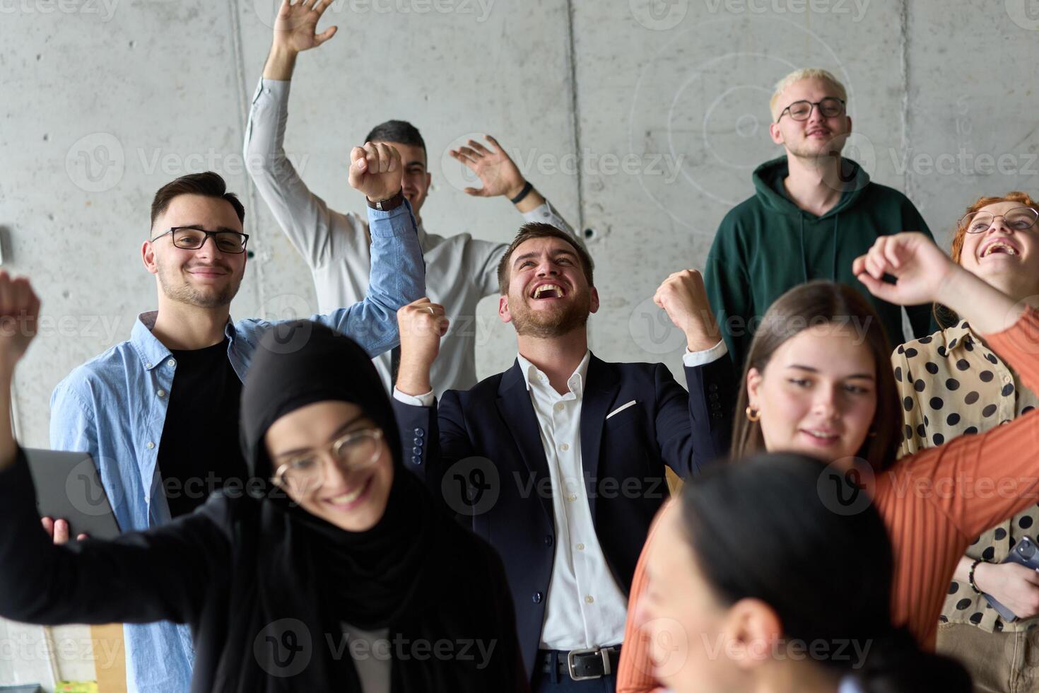 A diverse team of business professionals ecstatically celebrating their success in a modern office, expressing triumph and unity after achieving their goals photo