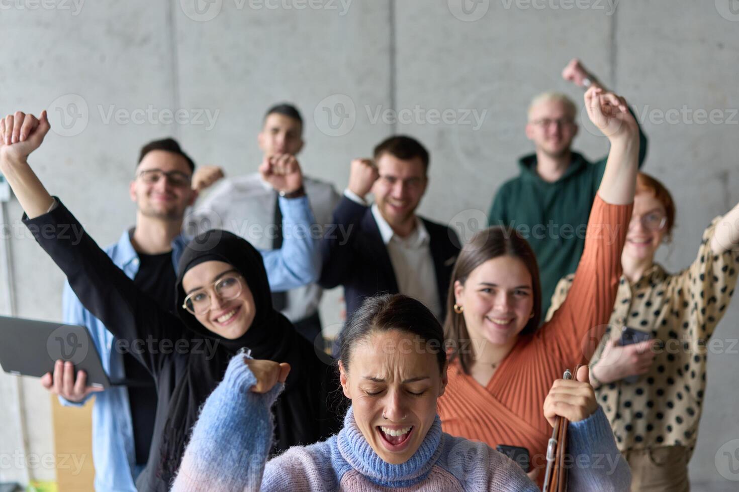A diverse team of business professionals ecstatically celebrating their success in a modern office, expressing triumph and unity after achieving their goals photo