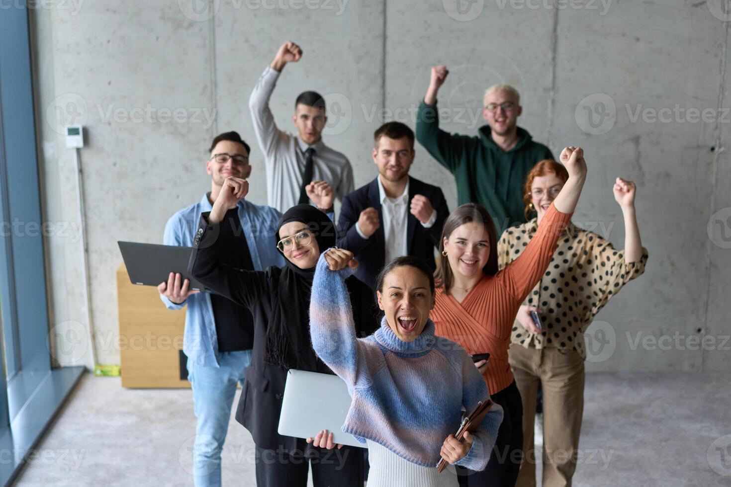 A diverse team of business professionals ecstatically celebrating their success in a modern office, expressing triumph and unity after achieving their goals photo