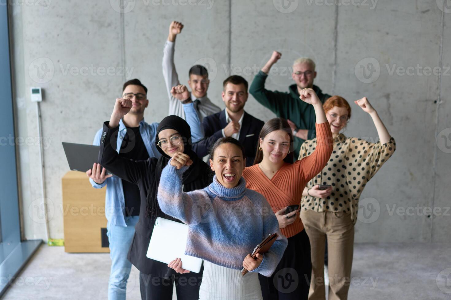 A diverse team of business professionals ecstatically celebrating their success in a modern office, expressing triumph and unity after achieving their goals photo