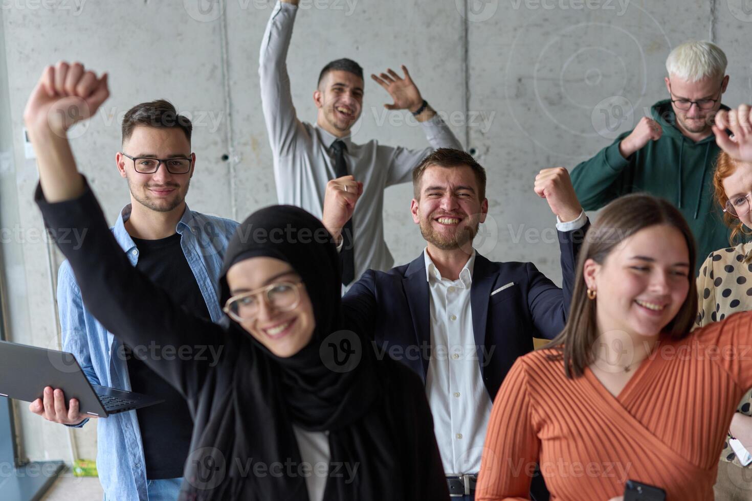 A diverse team of business professionals ecstatically celebrating their success in a modern office, expressing triumph and unity after achieving their goals photo