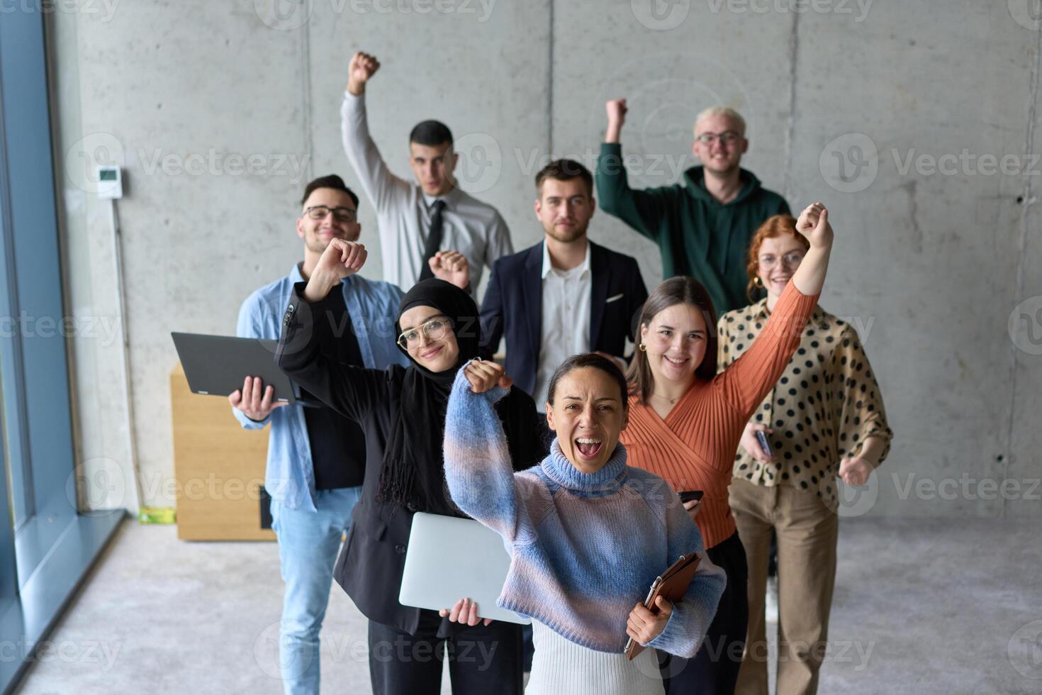 A diverse team of business professionals ecstatically celebrating their success in a modern office, expressing triumph and unity after achieving their goals photo