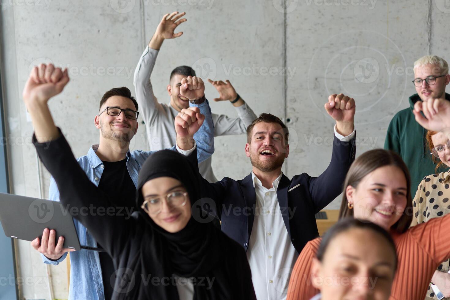 A diverse team of business professionals ecstatically celebrating their success in a modern office, expressing triumph and unity after achieving their goals photo